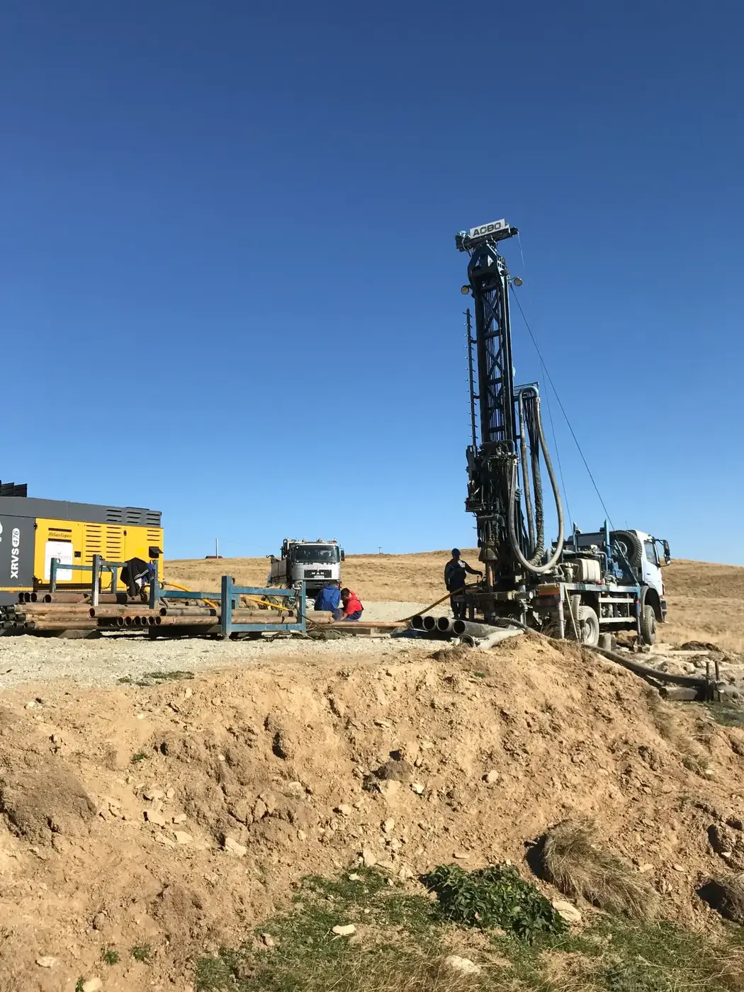 Instalație de foraj cu ciocan de fund și compresor Atlas Copco, pe un deal