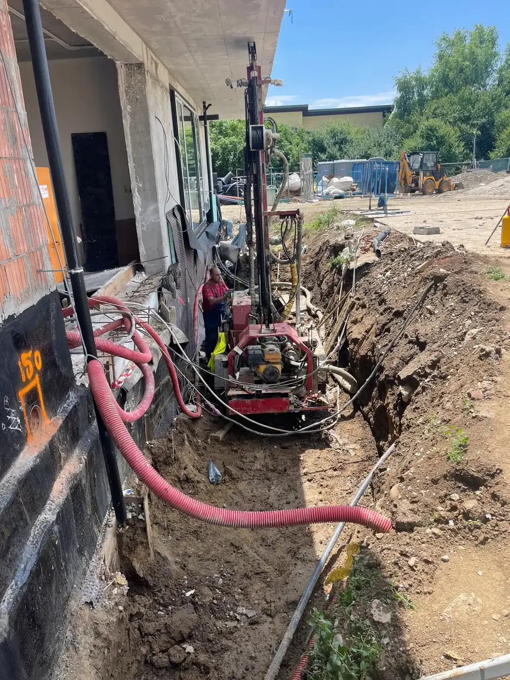 Instalație de foraj Comporsa într-o săpătură, lângă o clădire în construcție
